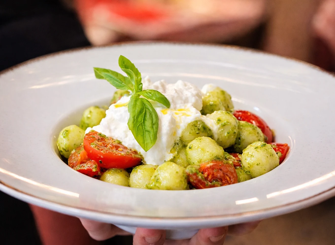 Gnocchi al pesto con burrata e pomodorini, serviti a mano