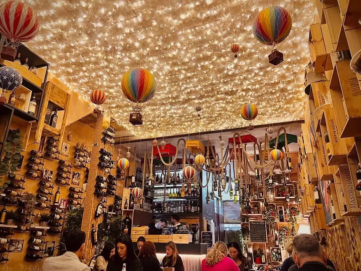 La sala dell'osteria: soffitto interamente coperto di piccole luci calde e mongolfiere colorate sospese