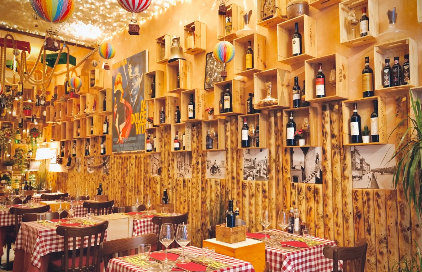 Parete della sala con casse di vino in legno, bottiglie toscane e il manifesto del film La Dolce Vita